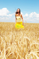 Beautiful young girl playing on a wheat field