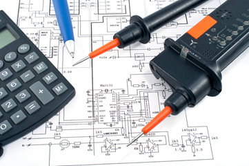 Voltage tester,calculator and pen on electrical diagram