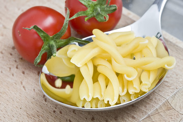 tomaten mit nudeln auf silberlöffel