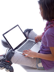 young girl relaxing with the laptop after inline skating