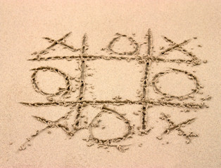 Tic tac toe game drawn in the sand on the beach
