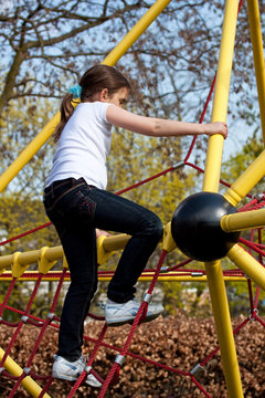 Girl Climbing A Frame In A Playground