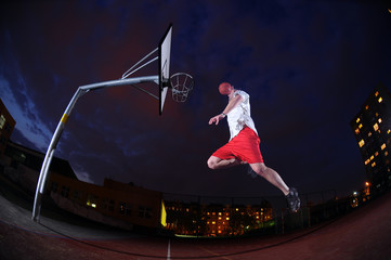 Basketball player slam dunking on an outdoors court © TP71