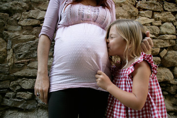 Girl kissing her pregnant mother's tummy