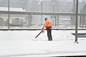 worker is cleaning the platform of a train station from snow