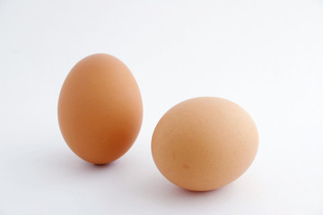 Two eggs with white background, one standing.