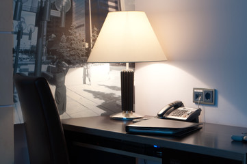 This is a table with lamp and phone on it