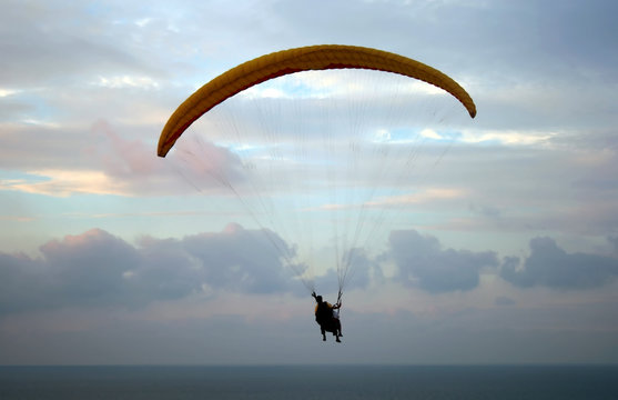 Flight of paraplane above Mediterranean sea on sunset