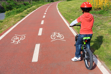 child with helmet on bicycle path