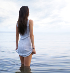 Young and sexy lady in a dress standing in the water