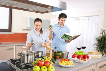 Young happy couple cook in kitchen with cookbook
