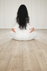 frau mit schwarzem haar beim yoga von hinten