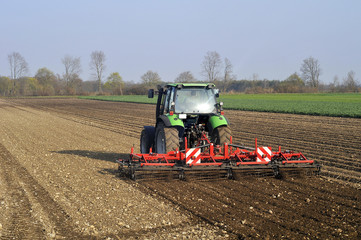 Bauer mit Traktor auf Feld im Frühjahr