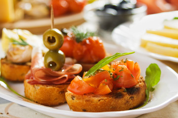 Bruschette with tomato, olives and prosciutto