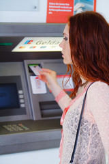 Frau holt Geld am Automat