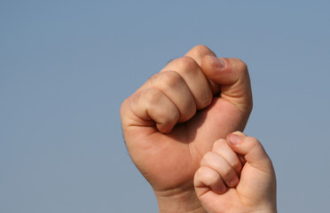 father and son fists on sky background