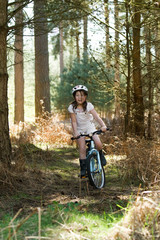 Naklejka premium Young Girl Riding her Bike in the Forest