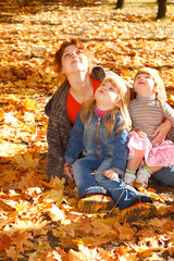 Mother and daughters in autumn leaves