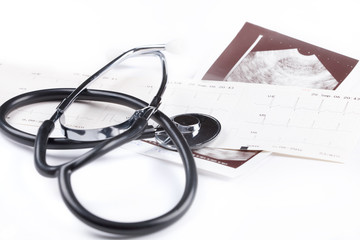 A stethoscope on the top of the EKG chart and USG picture