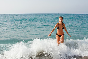 Young woman playing with waves on the beach