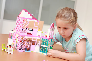 Cute little girl plays with doll's house