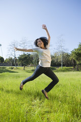 Hispanic girl jumping in a grassy field