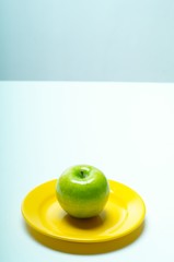 green apple on yellow plate