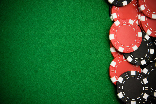 Black and red gambling chips on green felt background