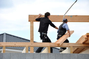 Zwei arbeitende Zimmermänner beim Dachbau, eine neue Konstruktion aus Holzbalken für den...