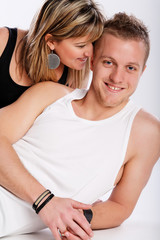 Young happy couple sits on white background.