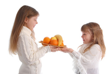 Two cheerful little girls with fruit on the white