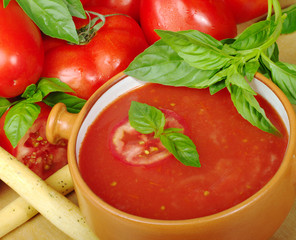 Tomato soup in bowl with tomatoes and basil (Selective Focus)