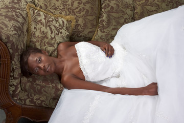 Young ethnic black woman bride in wedding dress on couch