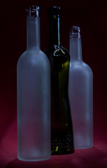 wo white, opaque and dark bottles on a red background