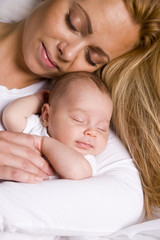 Fototapeta na wymiar Mother holding baby boy in her arms peacefully asleep