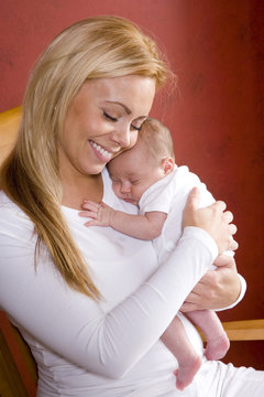 Mother Holding Newborn Baby In Rocking Chair