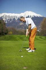 Man striking a golf ball at the hole - 22222261