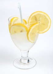 Water with lemon slices, ice and a straw in a glass cup