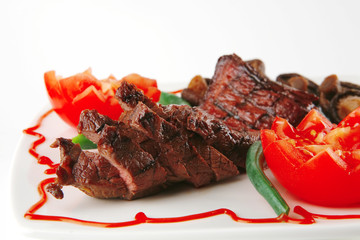 fillet mignon on a white plate and tomatoes