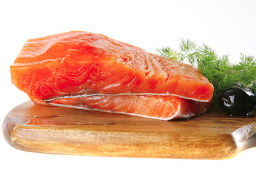 pink smoked salmon on wooden plate with white cheese