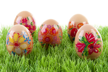 decorated chicken eggs in grass over white background