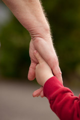 Mature woman holding hands with young child