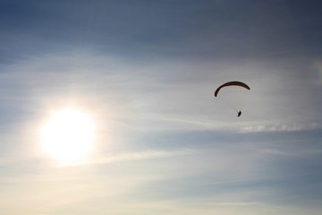 Paraglider flying towards the sun
