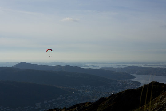 Paraglider flying over Norwegian coastal landscape