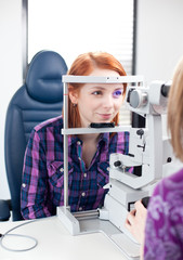 optometry concept - pretty young woman having her eyes examined