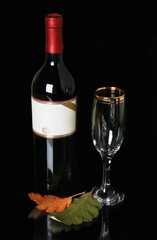 Bottle red blame with empty label and goblet on black