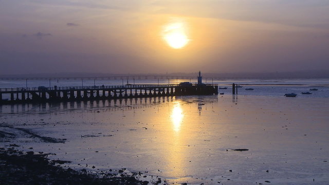 Pier in river at sunset