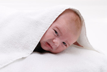 Fototapeta na wymiar petit bébé regardant de dessous d'un essuie