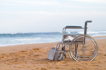 empty wheelchair on beach - Powered by Adobe
