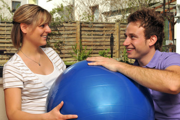 Schwangere Frau und werdender Vater mit Gymnastikball